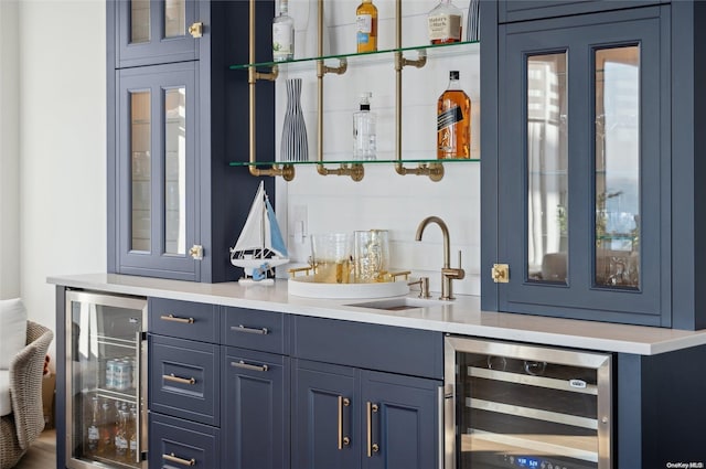 bar with wine cooler, blue cabinets, and sink