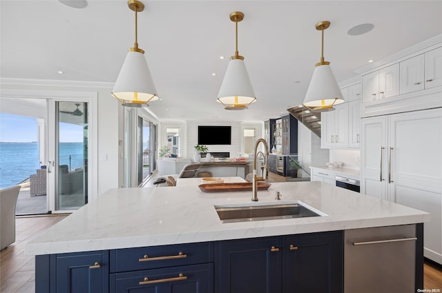 kitchen with white cabinetry, a kitchen island with sink, pendant lighting, a water view, and sink