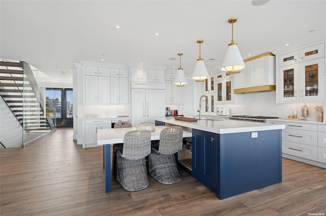 kitchen featuring pendant lighting, a large island with sink, a kitchen bar, white cabinetry, and dark hardwood / wood-style floors