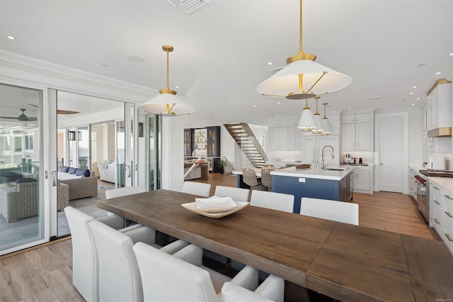 dining room with sink, crown molding, and light hardwood / wood-style flooring