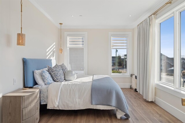 bedroom with crown molding, hardwood / wood-style floors, and multiple windows