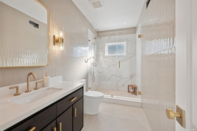 bathroom with toilet, vanity, tile walls, tile patterned flooring, and a shower with shower door