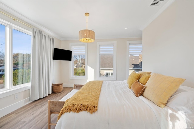 bedroom with light wood-type flooring, multiple windows, and ornamental molding