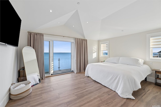 bedroom featuring light hardwood / wood-style floors, access to outside, a water view, and vaulted ceiling