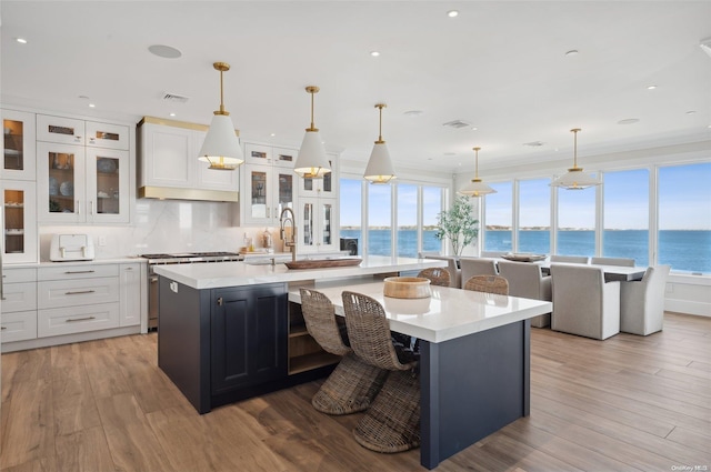 kitchen featuring decorative light fixtures, a kitchen bar, a kitchen island with sink, and a water view