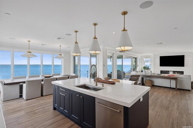 kitchen featuring dishwasher, pendant lighting, sink, an island with sink, and a water view