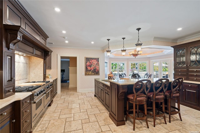 kitchen featuring a center island, hanging light fixtures, a kitchen bar, dark brown cabinets, and ornamental molding