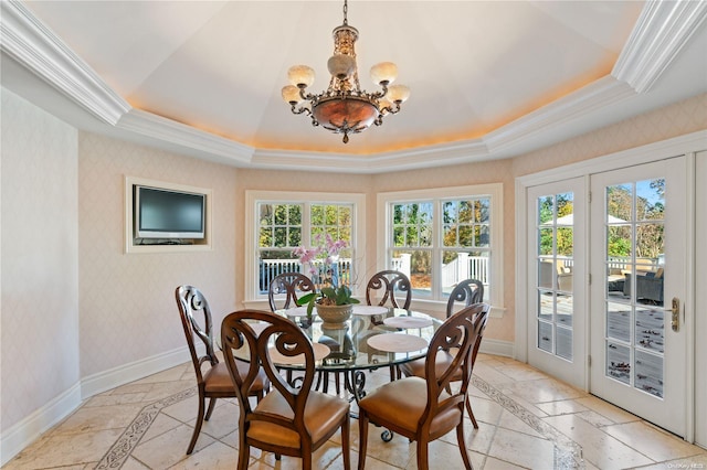 dining space with a tray ceiling, crown molding, and a notable chandelier