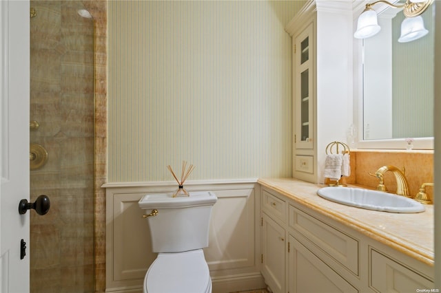 bathroom with a tile shower, vanity, and toilet