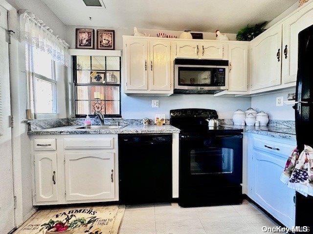 kitchen with white cabinetry, sink, black appliances, and light stone counters