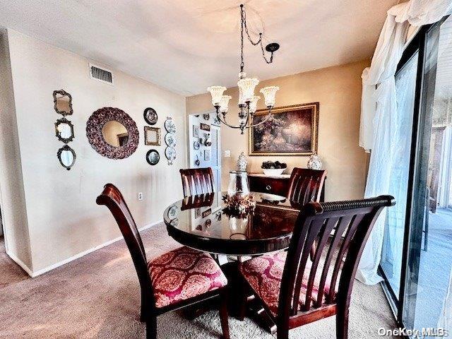 dining area with carpet and a notable chandelier