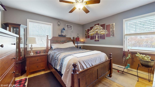 bedroom featuring ceiling fan, baseboard heating, and light hardwood / wood-style flooring