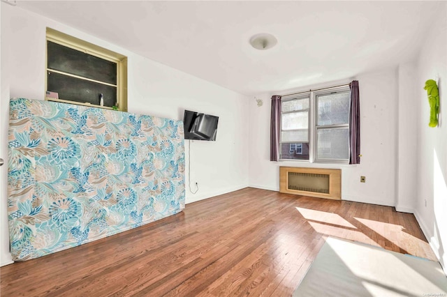 unfurnished living room featuring radiator heating unit and hardwood / wood-style floors