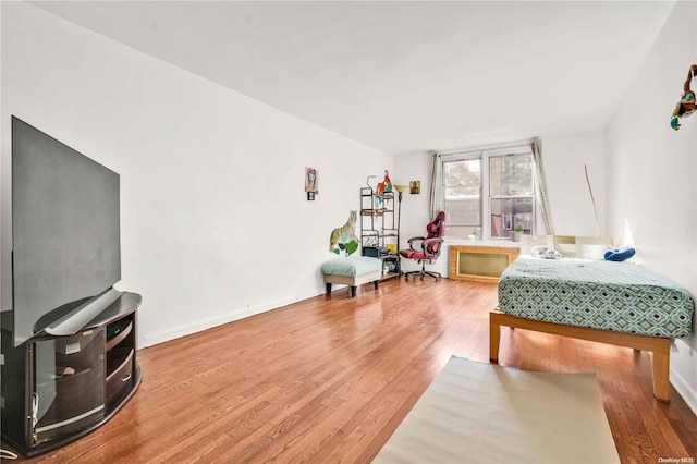 bedroom with hardwood / wood-style floors and radiator heating unit