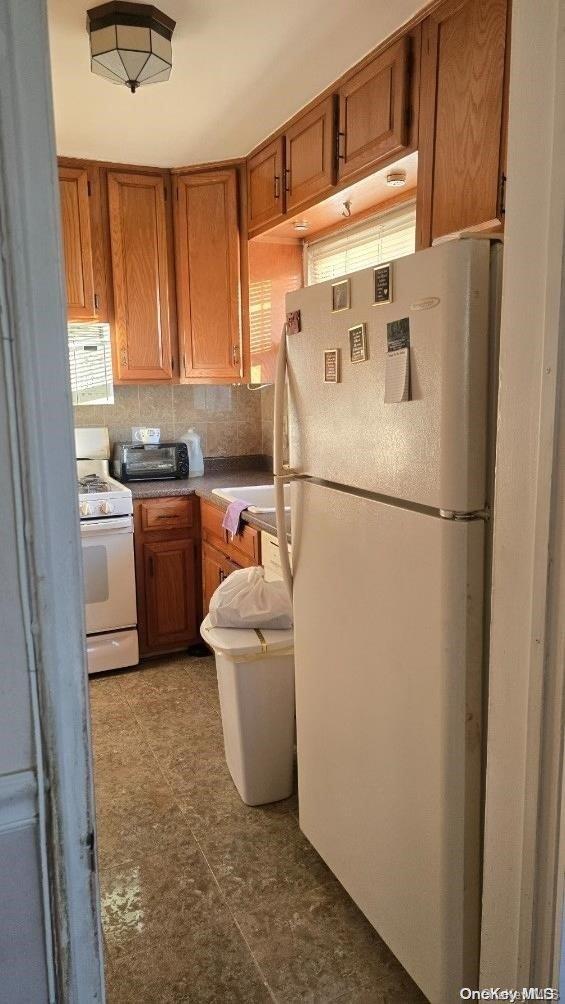 198-02 Pompeii Ave Unit 1B, Hollis, NY 11423 - kitchen with white appliances, brown cabinets, and backsplash