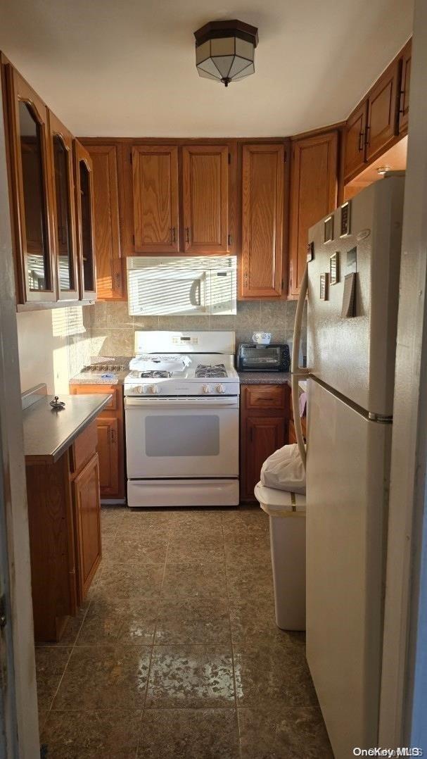 198-02 Pompeii Ave Unit 1B, Hollis, NY 11423 - kitchen featuring white appliances, brown cabinets, and tasteful backsplash
