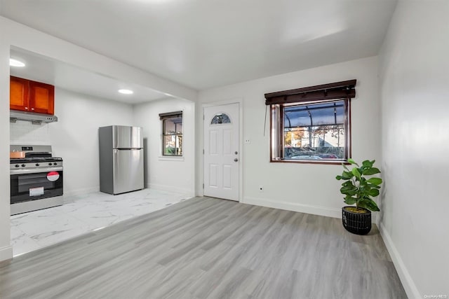 interior space featuring decorative backsplash, light hardwood / wood-style floors, and appliances with stainless steel finishes