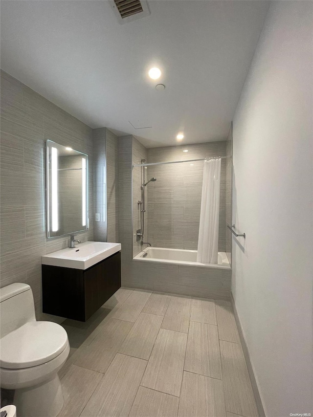 full bathroom with shower / bath combo with shower curtain, vanity, tile walls, and toilet