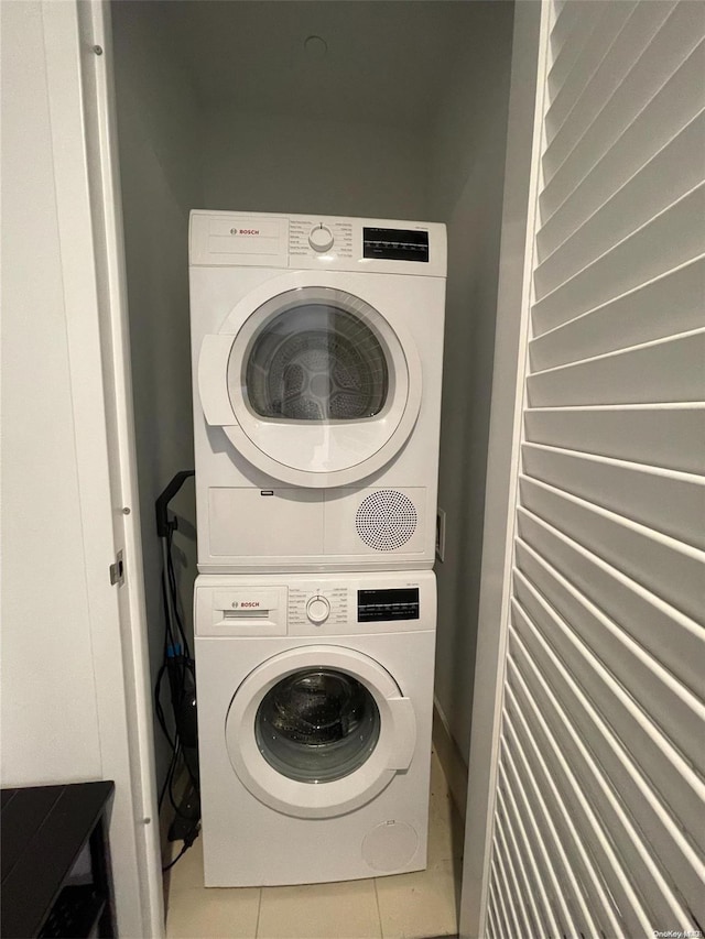 laundry area with stacked washer and dryer and tile patterned flooring