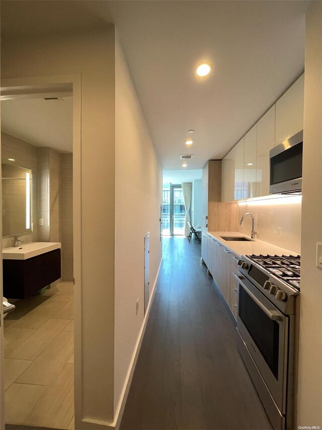 kitchen with dark hardwood / wood-style floors, sink, white cabinetry, and stainless steel appliances