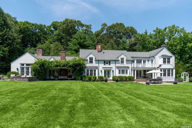 rear view of property with a lawn, a patio area, and french doors