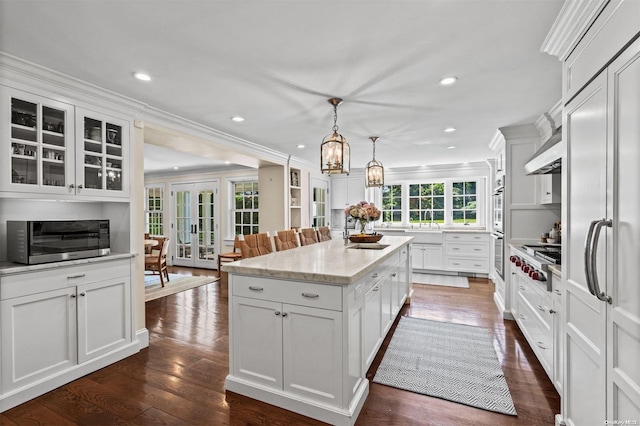 kitchen with ornamental molding, decorative light fixtures, a center island, dark hardwood / wood-style floors, and white cabinetry