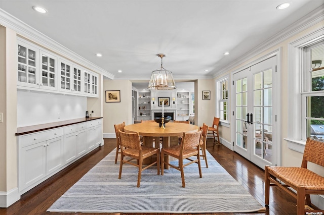 dining space featuring a chandelier, dark hardwood / wood-style flooring, crown molding, and french doors