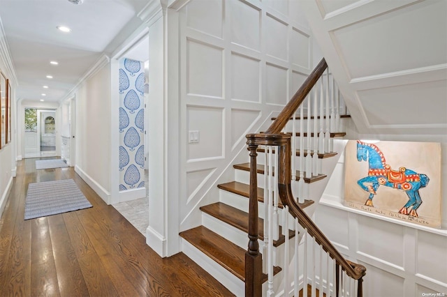 stairs with wood-type flooring and ornamental molding