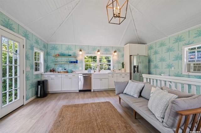 living room with a notable chandelier, light hardwood / wood-style floors, lofted ceiling, and a wealth of natural light