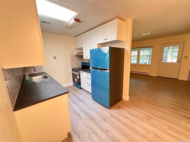 kitchen featuring black range oven, decorative backsplash, white cabinets, and stainless steel refrigerator