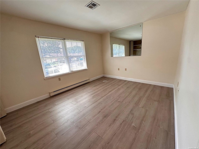 unfurnished room featuring light wood-type flooring and a baseboard heating unit