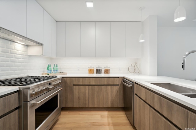 kitchen with decorative light fixtures, white cabinetry, stainless steel appliances, and light hardwood / wood-style flooring