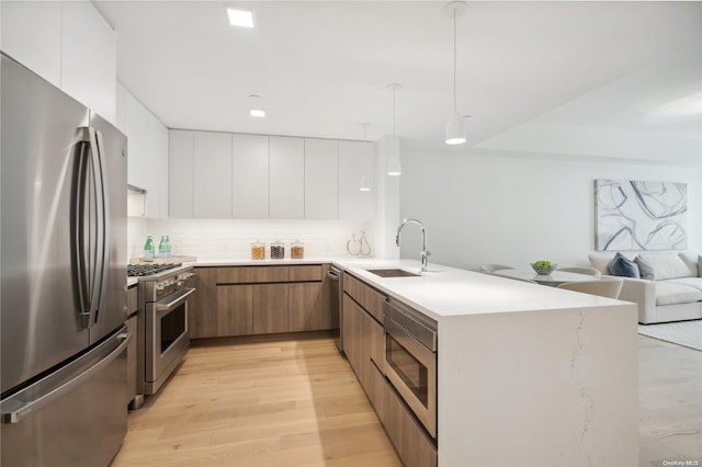 kitchen with light wood-type flooring, white cabinetry, sink, and appliances with stainless steel finishes