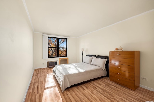 bedroom featuring a wall mounted air conditioner, light hardwood / wood-style floors, and ornamental molding