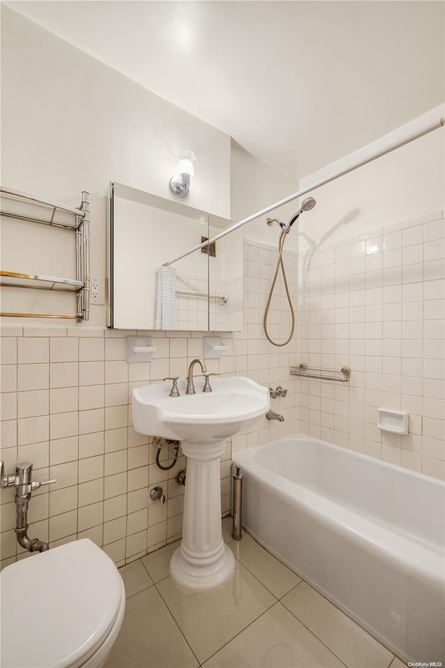 bathroom with tile patterned flooring, tiled shower / bath combo, toilet, and tile walls