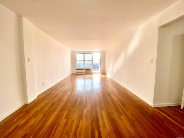 empty room with dark wood-type flooring and radiator heating unit