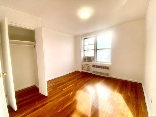 unfurnished bedroom with dark hardwood / wood-style flooring, a closet, cooling unit, and radiator heating unit