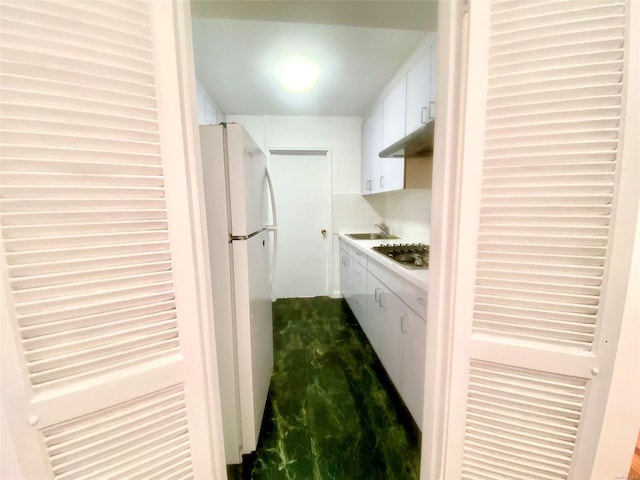 kitchen featuring white refrigerator, white cabinets, and stainless steel gas stovetop