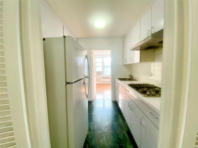 kitchen featuring white cabinets, stainless steel gas cooktop, white fridge, tasteful backsplash, and radiator