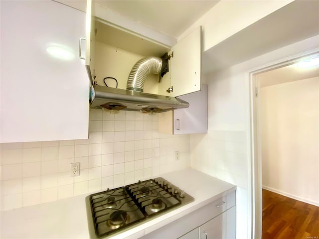 kitchen featuring dark wood-type flooring, extractor fan, gas cooktop, tasteful backsplash, and white cabinets