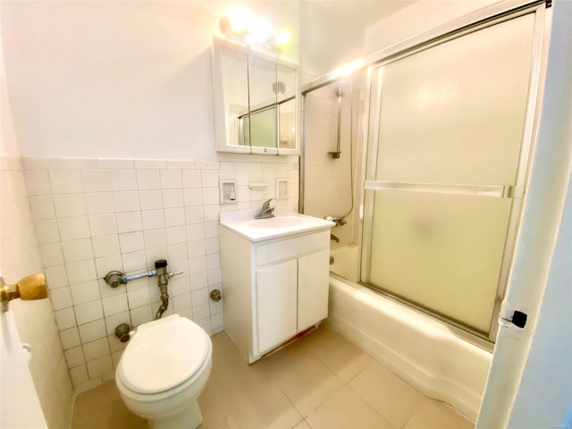 full bathroom featuring tile patterned flooring, toilet, vanity, tile walls, and bath / shower combo with glass door