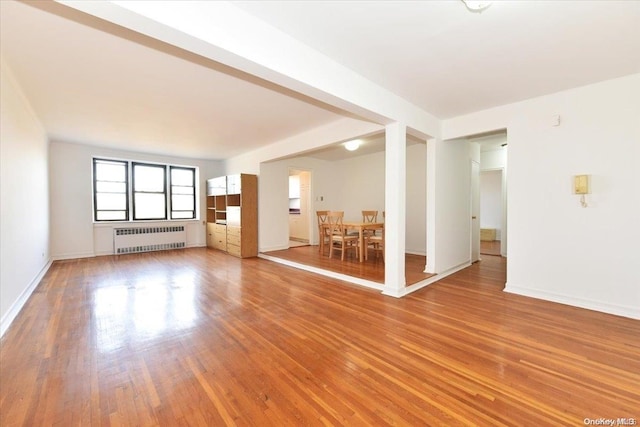 unfurnished living room featuring hardwood / wood-style flooring and radiator heating unit