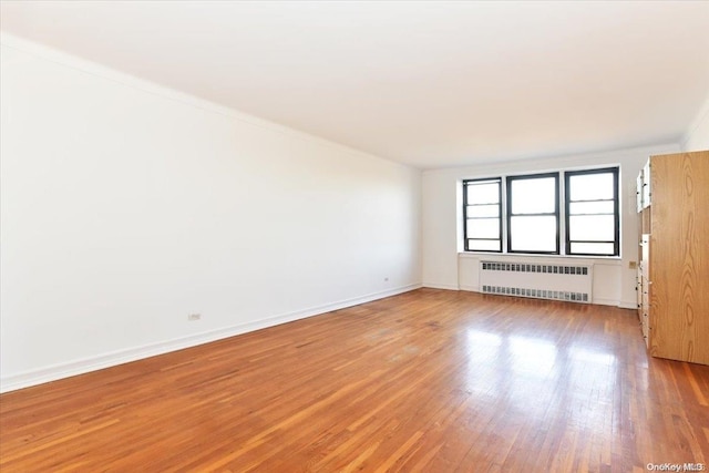 unfurnished room featuring hardwood / wood-style flooring and radiator heating unit