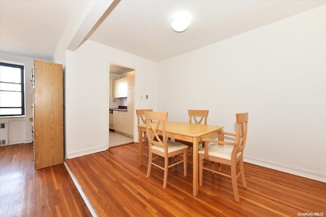 dining space featuring radiator, beamed ceiling, and wood-type flooring