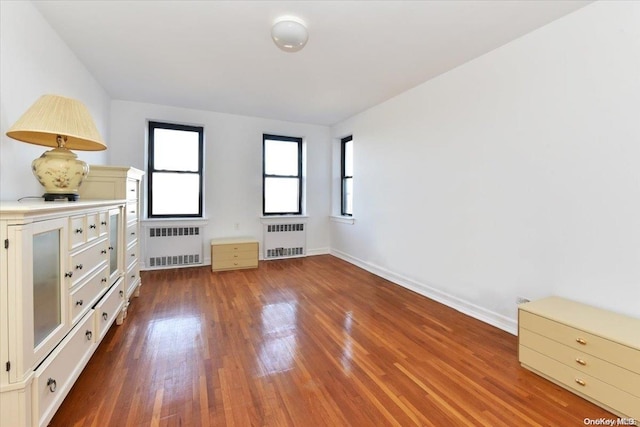 unfurnished bedroom with hardwood / wood-style flooring and radiator