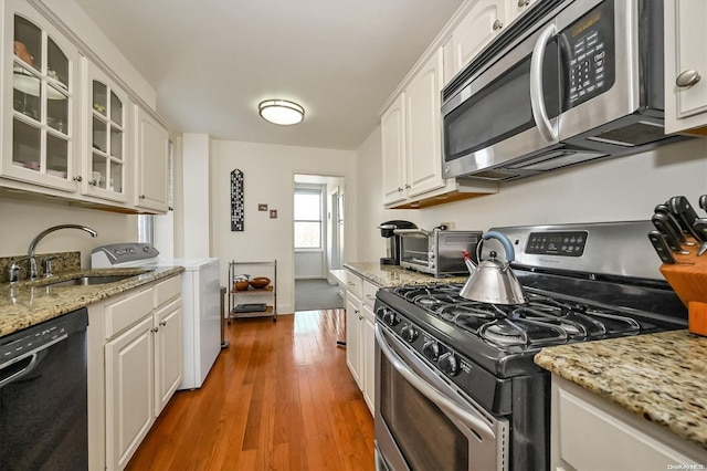 kitchen with white cabinetry, sink, stainless steel appliances, and wood-type flooring