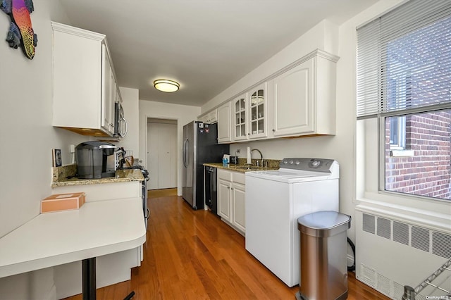 kitchen featuring white cabinetry, sink, radiator heating unit, dark wood-type flooring, and washer / dryer