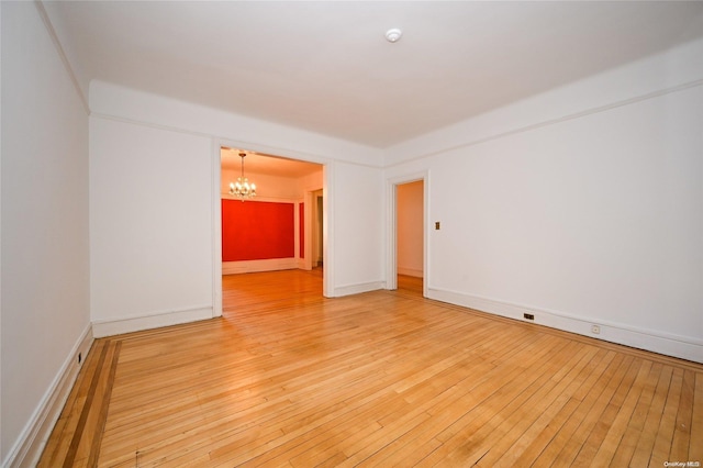 unfurnished room featuring a chandelier and wood-type flooring