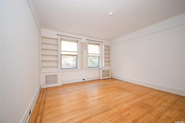 spare room featuring radiator heating unit and light wood-type flooring