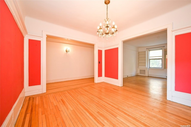 spare room with hardwood / wood-style floors and a chandelier